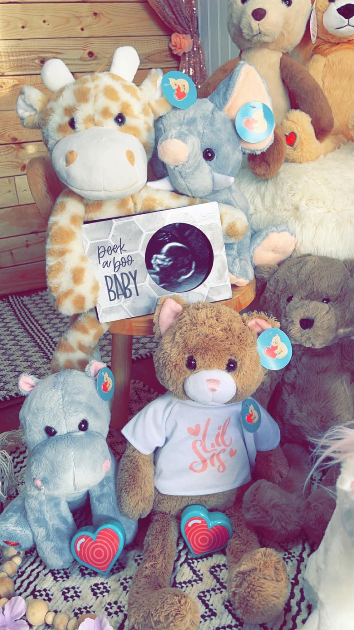 A Peek A Boo Baby keepsake frame holding a sonogram, surrounded by plush animals with heartbeat recorder hearts.