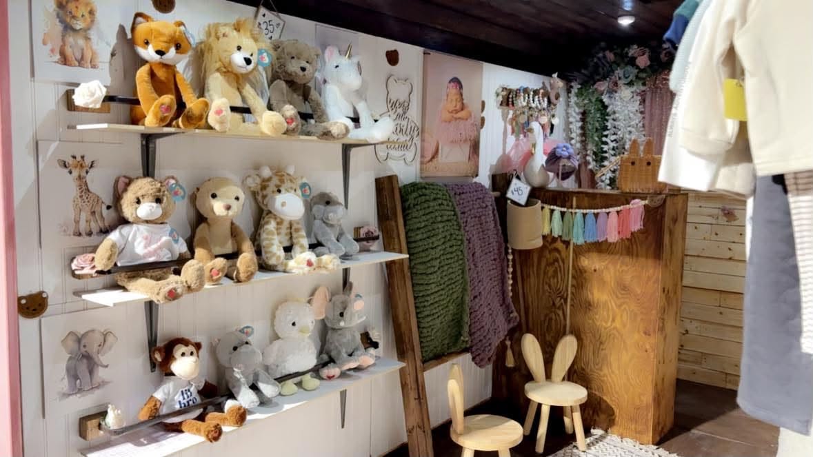 The Baby Beats studio: shelves of plush animals, chunky knit blankets and hanging baby clothes in a warm wood-panelled room.